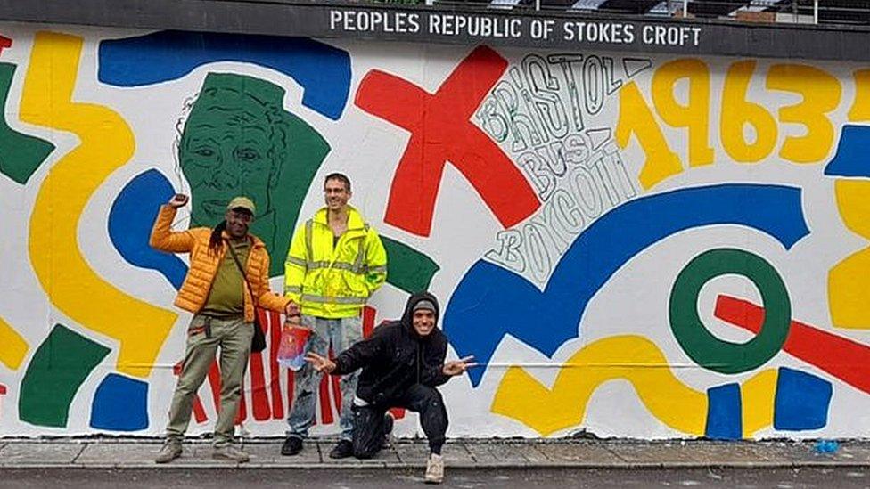 Three men standing in front of the mural