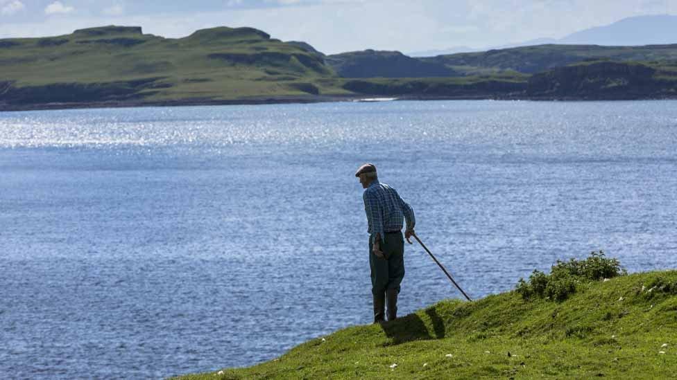 A farmer looks out over Loch Harport near Coillure on Isle of Skye