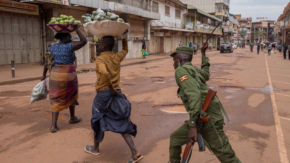 A police officer beats a female orange vendor on a street in Kampala, Uganda, on March 26, 2020, after Ugandan President Yoweri Museveni directed the public to stay home for 32 days