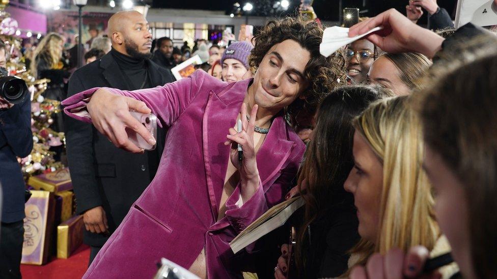 Timothee Chalamet takes selfies with fans as he arrives for the world premiere of Wonka at the Royal Festival Hall in London