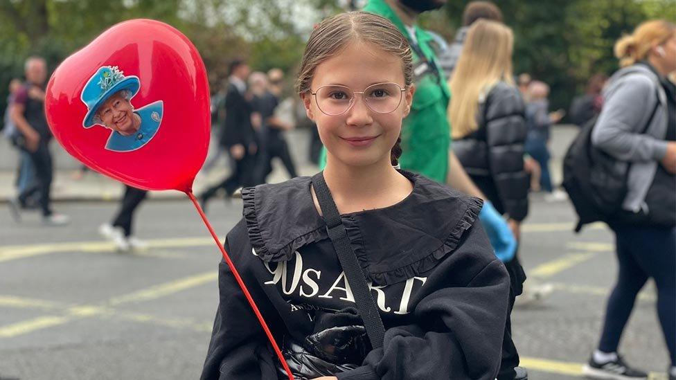 Saskia holding a balloon with the Queen on it.