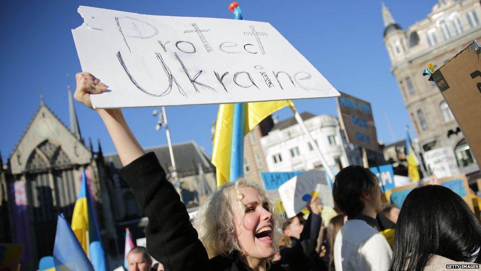 A picture of a person holding a 'Protect Ukraine' banner in Amsterdam