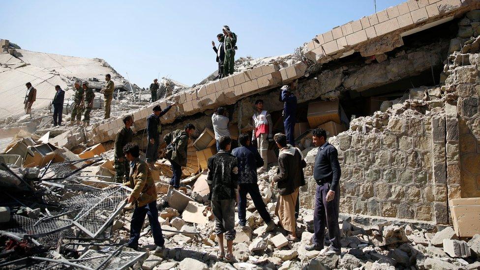 Policemen and people search for victims at the site of a Saudi-led air strike on a police headquarters in Sanaa, Yemen (18 January 2016)