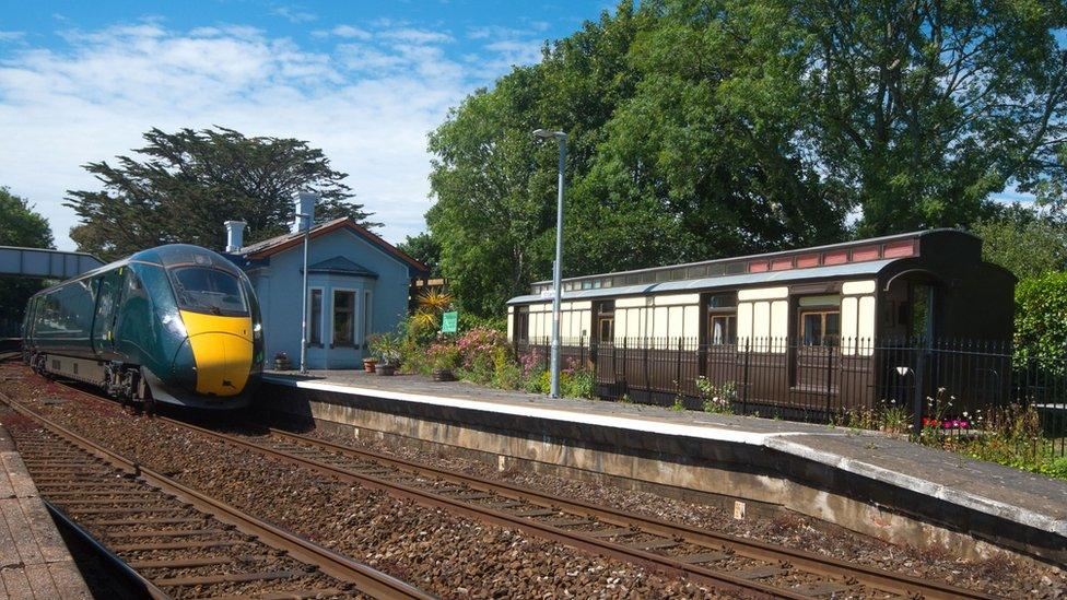 Old Travelling Post Office railway carriage and a passing modern train at St Germans station