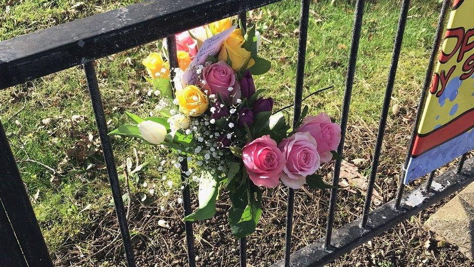 Flowers tied to a railing at the scene of the incident