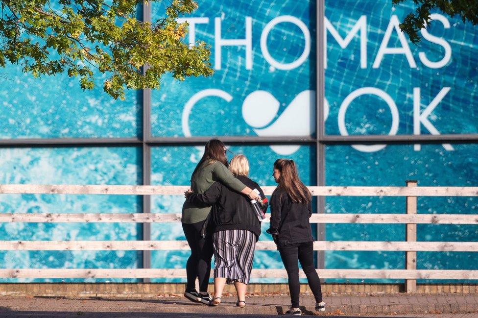 Three women hug outside office