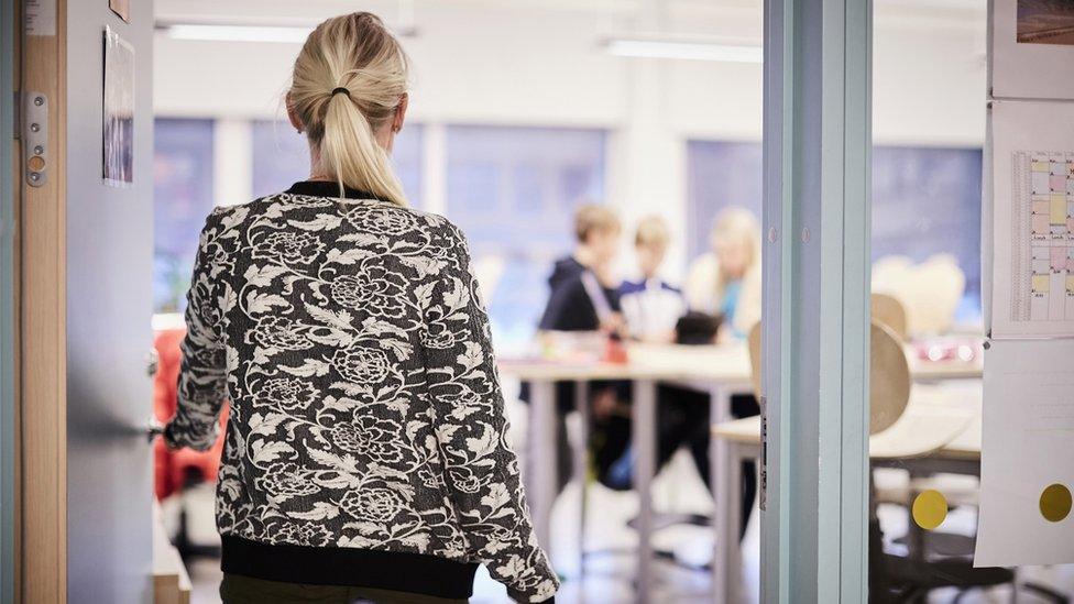 Stock image of adult walking into classroom