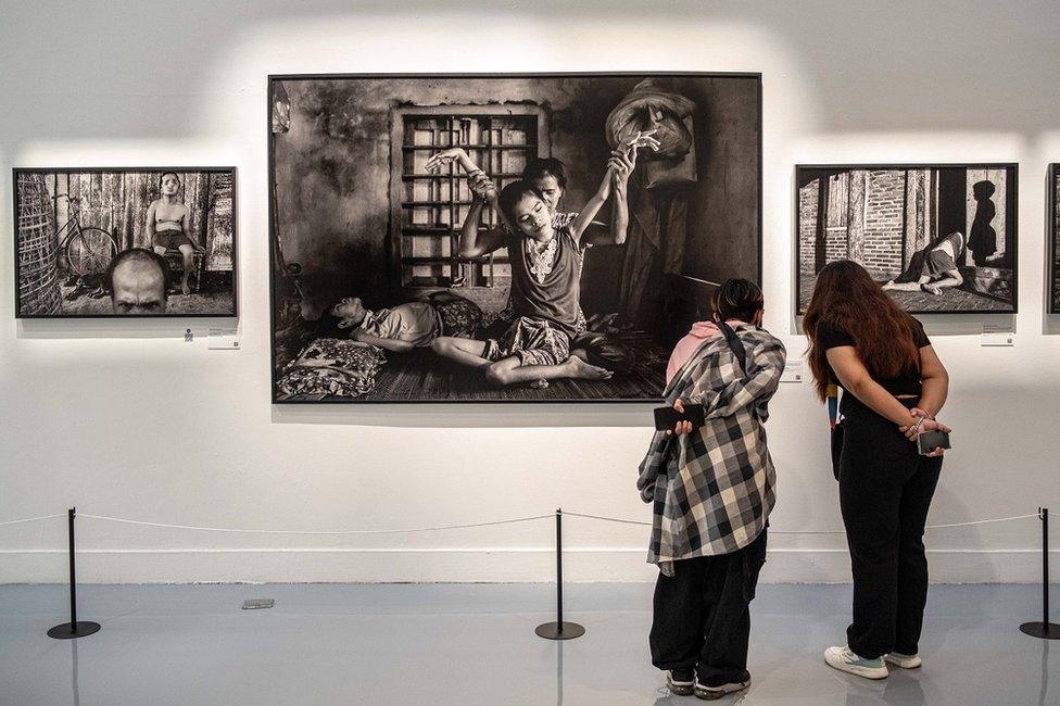 Two women look at a photo of of a young Vietnamese who was affected by Agent Orange