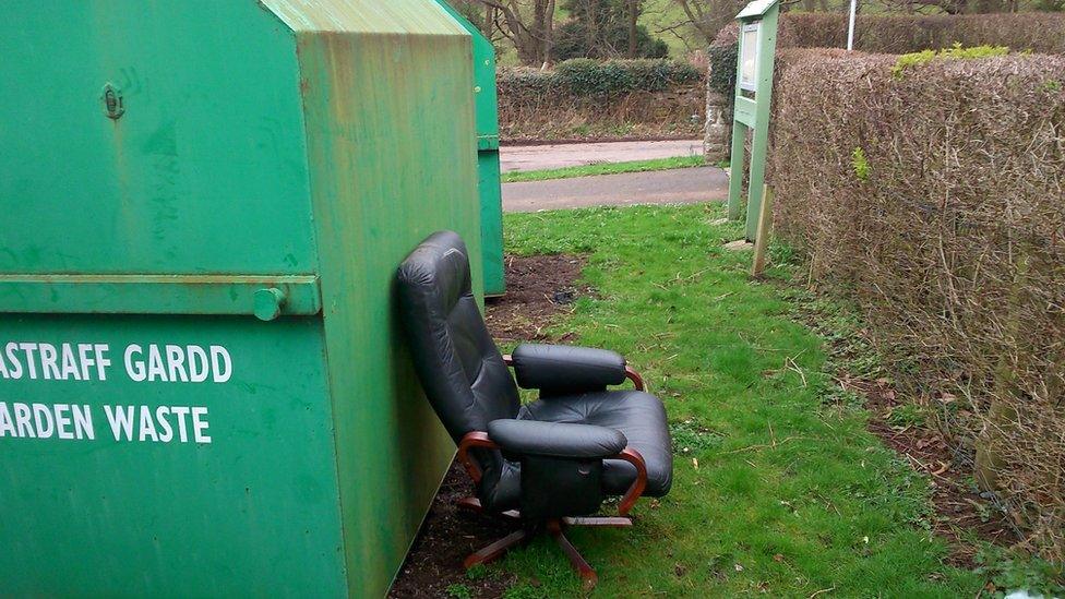 chair dumped next to garden waste bin