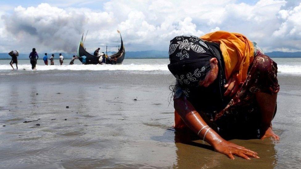 An exhausted Rohingya refugee woman touches the shore after crossing the Bangladesh-Myanmar border by boat through the Bay of Bengal, in Shah Porir Dwip, Bangladesh September 11, 2017.