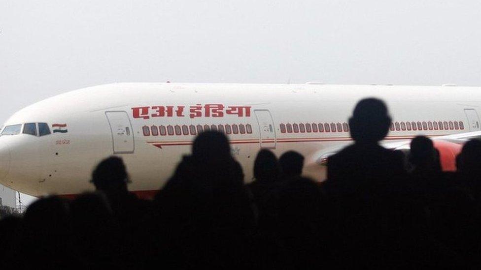 Air India employees look at the newly acquired Boeing 777-200 LR aircraft, 'ASSAM', as it stands on the tarmac of the Chattrapati Shivaji International airport in Mumbai, 30 July 2007, on the eve of Air India?s inaugural non-stop operations in the Mumbai-New York sector. I