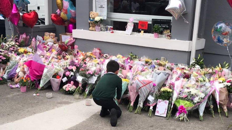 A young boy lays a floral tribute to Saffie Roussos