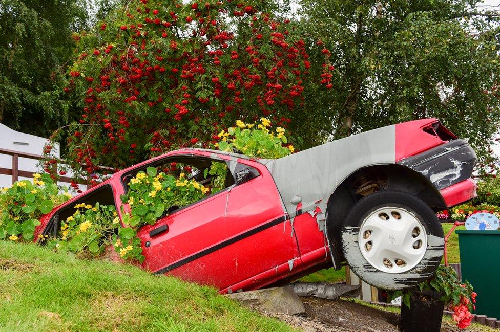 An upcycled car bursting with nasturtiums at the city's recycling centre