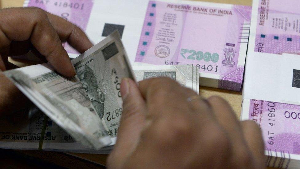 A bank staff member counts Indian 500 rupee notes to give to customers on November 24, 2016, in the wake of the demonetisation of old 500 and 1000 rupee notes in Mumbai.