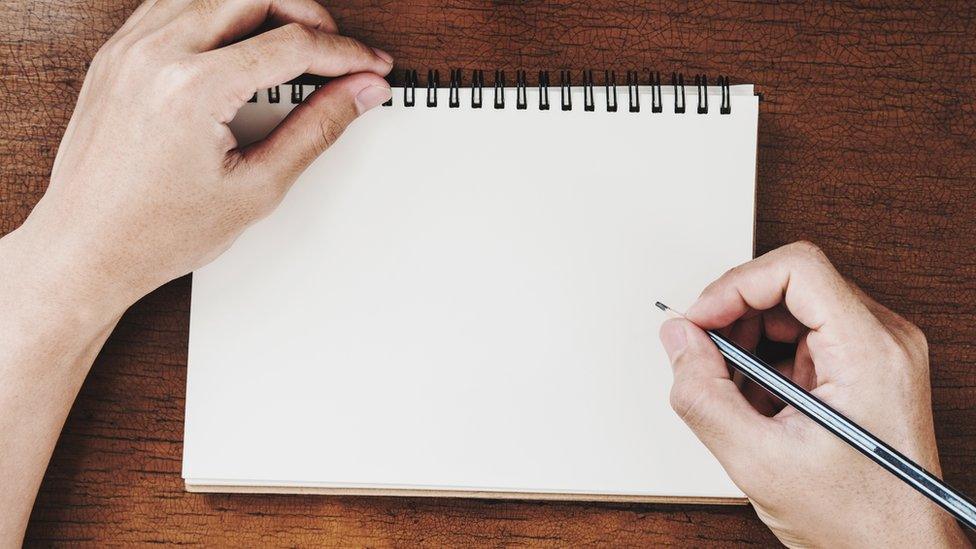 A man's hands by a notebook