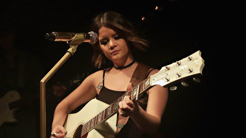 Maren Morris singing on stage with her guitar