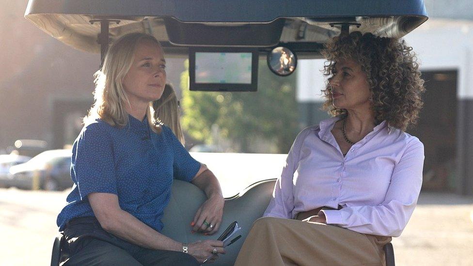 Katie Razzall and Donna Langley on the back of a golf cart