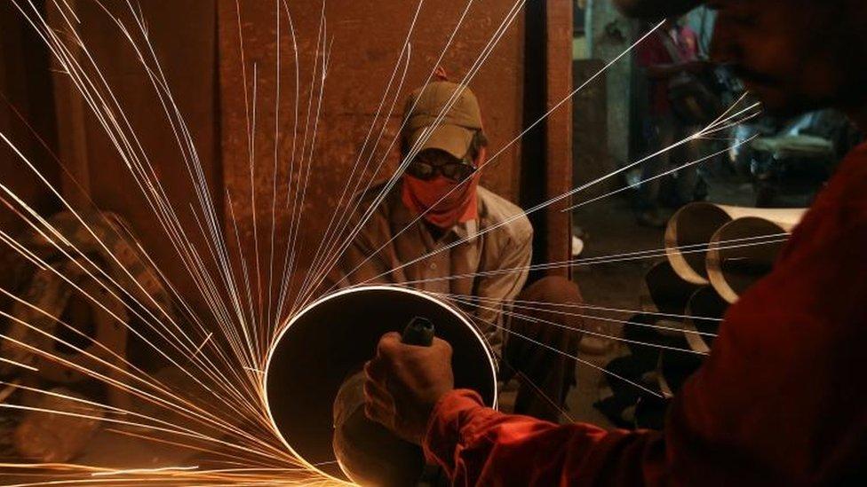 A worker cuts metal inside a workshop manufacturing metal pipes in Mumbai, India