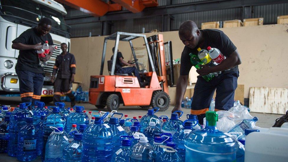 Workers collect bottles of water to distribute to communities with no water in South Africa