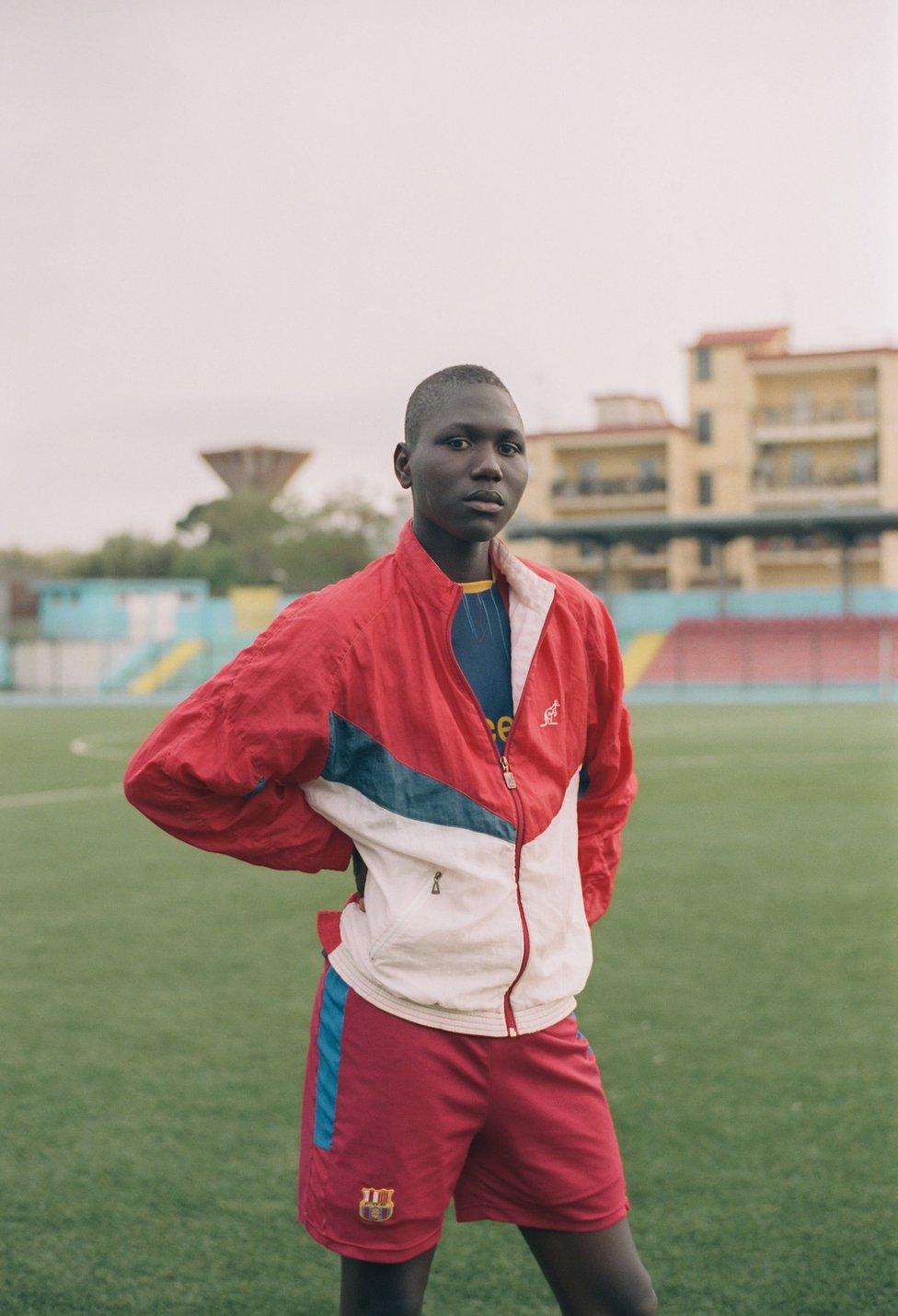 A boy wearing a tracksuit in a stadium