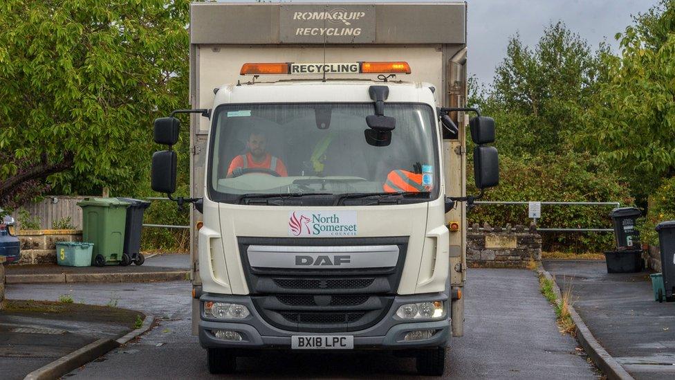 image of a waste collection lorry being driven down a street.