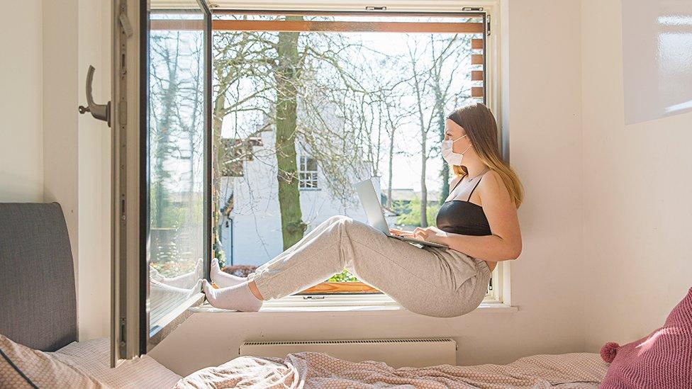 A woman in a room looking out the window