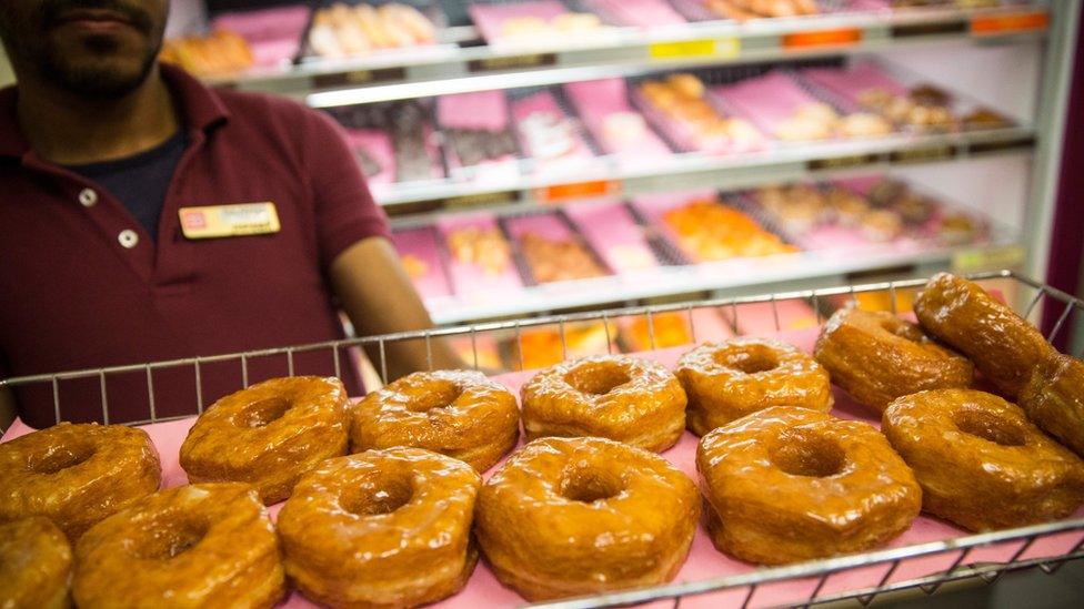 A Dunkin' Donuts employee displays a fresh tray of 'croissant doughnuts' on November 3, 2014 in New York City