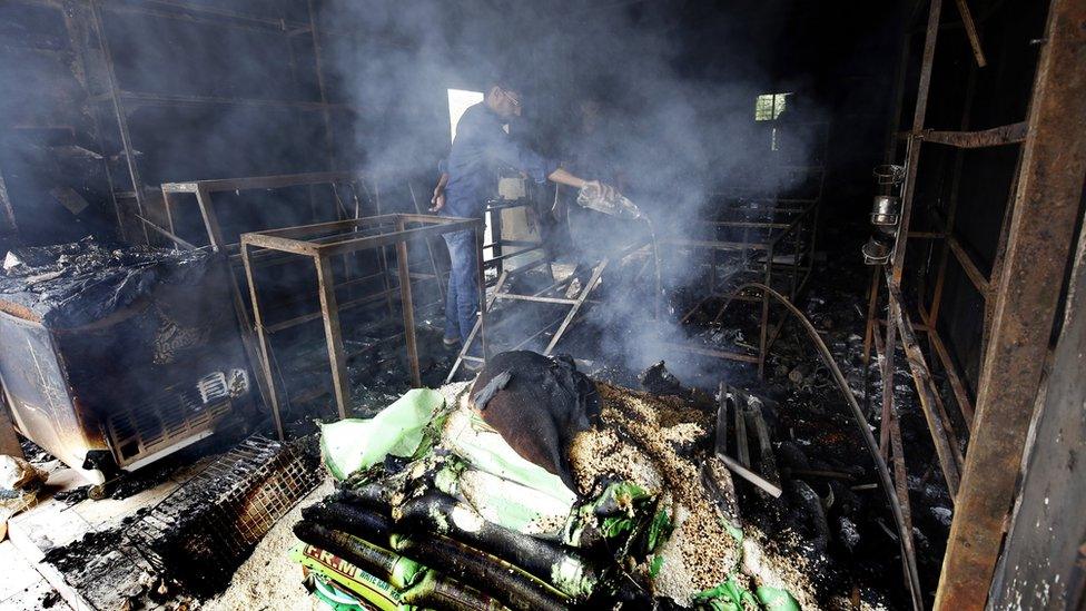 A Sri Lankan Muslim tries to put out the remaining embers in his fire-gutted business in Digana town, Kandy in Sri Lanka, 7 March 2018