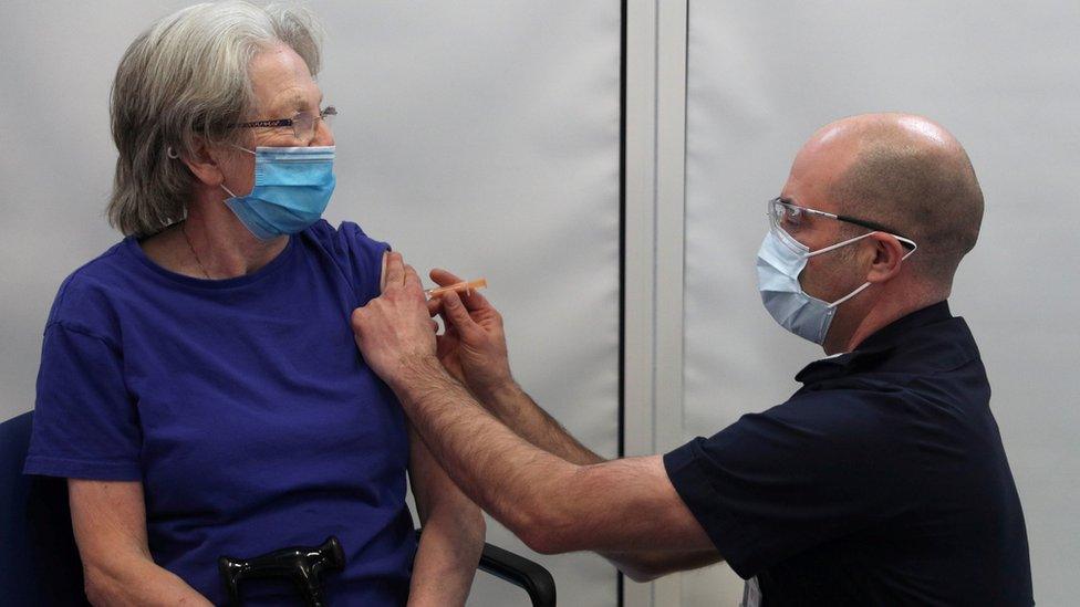 Woman receives a Covid-19 vaccine from a member of the Hampshire Fire and Rescue Service