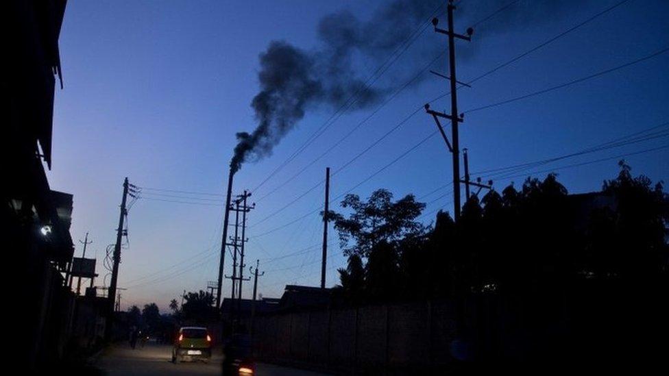 Traffic moves as smoke emits from the chimney of a factory on the outskirts of Gauhati, India, Sunday, Oct. 2, 2016