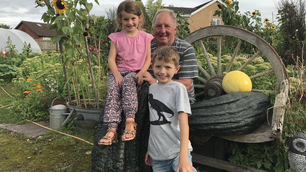 Phillip Vowles and his grandchildren Charlie and Sophia on top of a giant marrow