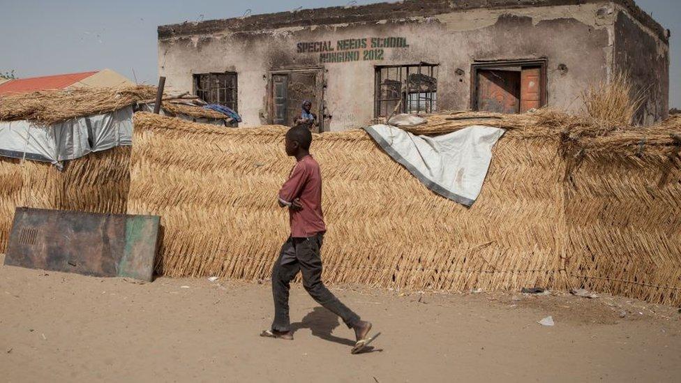 A boy walks past a school burnt in a camp for internally displaced people at Monguno district of Borno State on February 14, 2017