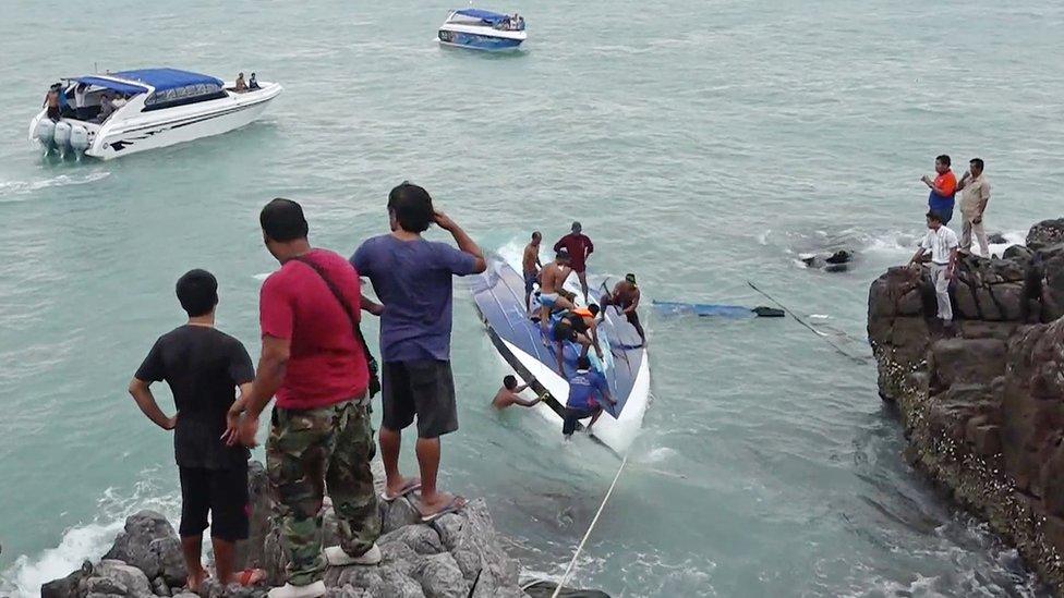 A capsized boat and rescue workers