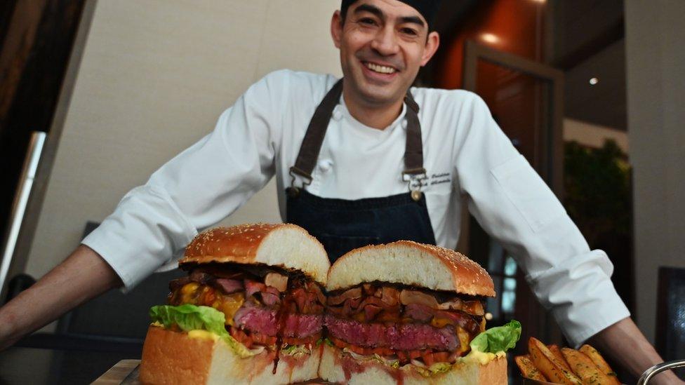 chef-standing-with-a-cut-Golden-Giant-Burger.