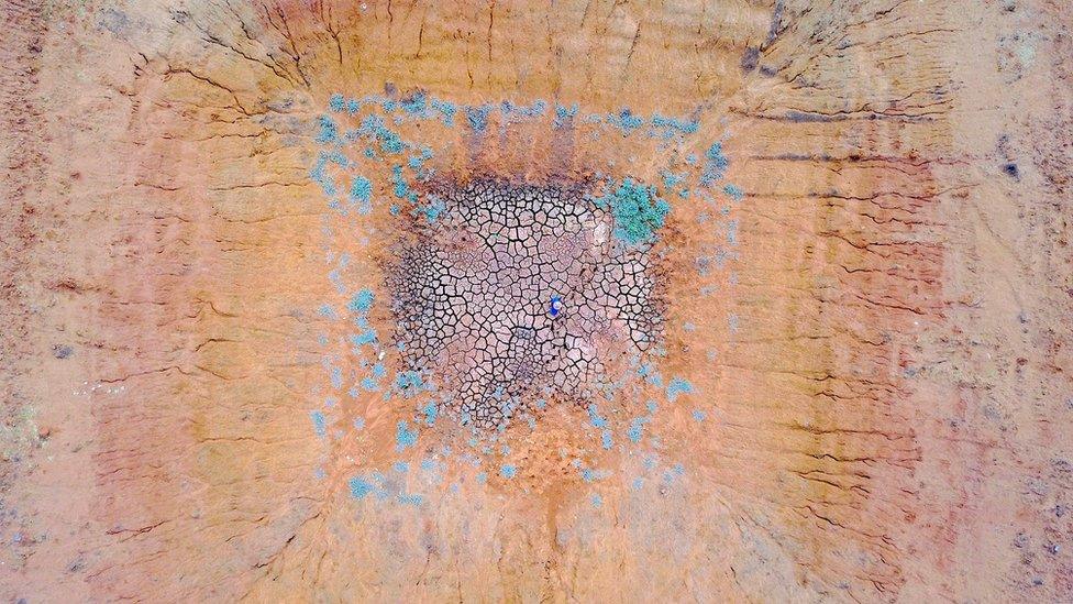 Farmer Ash Whitney stands in the middle of a dried-up dam