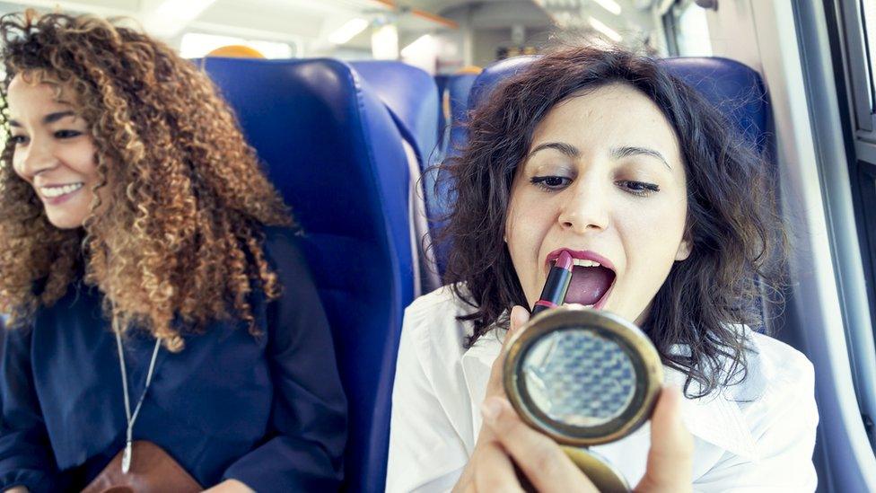 A woman doing her make-up on the train