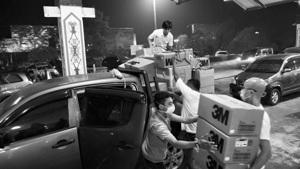 A team of workers from Singapore unloads cartons of N95 facial masks