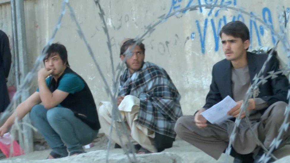 Afghan men wait at a passport office