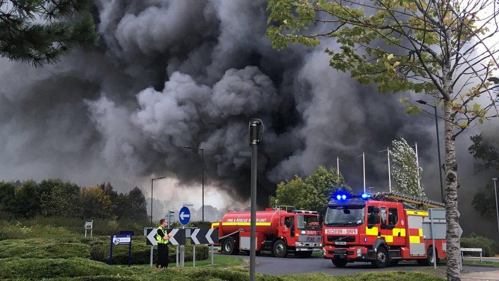 A photo shows plumes of black smoke coming from the building