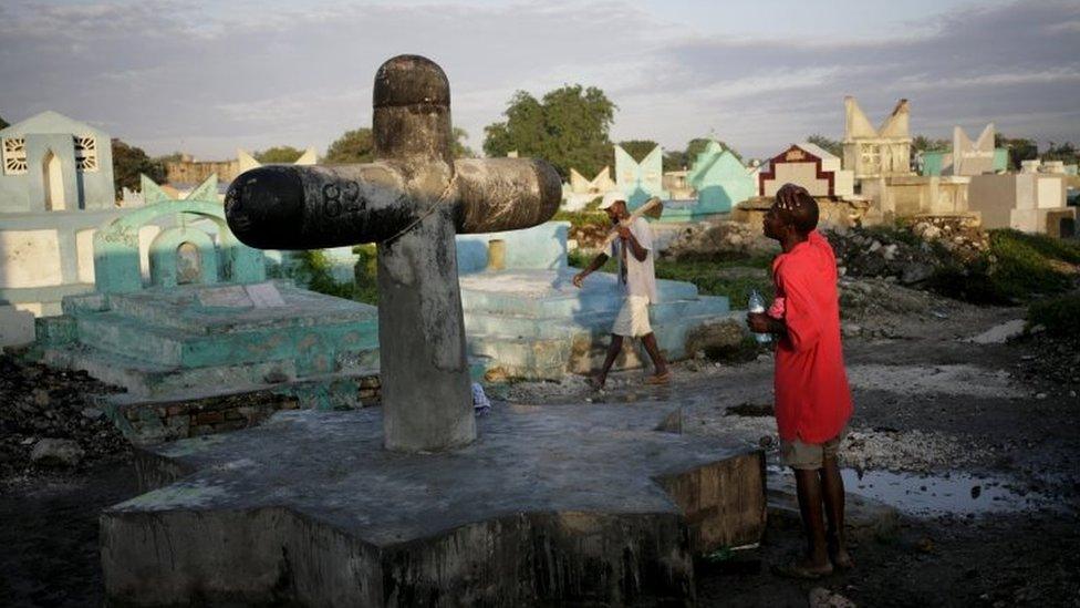 A voodoo believer prays at Baron Samdi cross in the cemetery of Croix des Bouquets on the outskirts of Port-au-Prince on 1 November, 2015