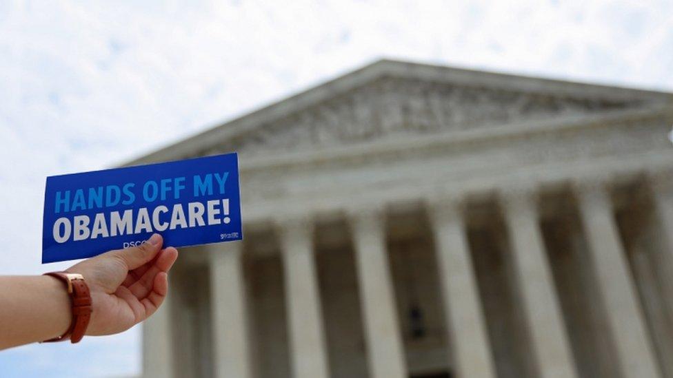 A "Hands off my Obamacare" leaflet is held up outside the US Supreme Court