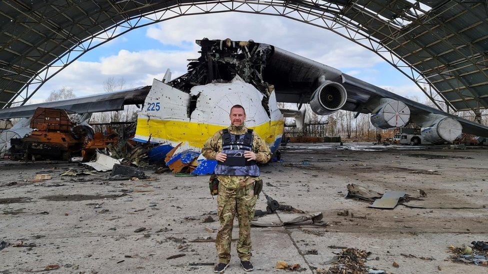 Steve Brooks standing in front of a damaged aeroplane