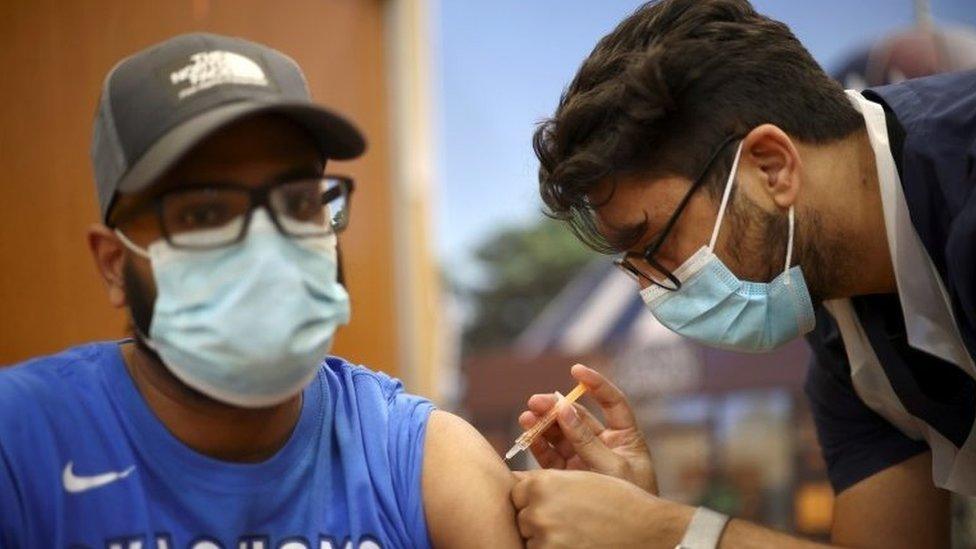 A man receives an injection with a dose of AstraZeneca coronavirus vaccine, at a vaccination centre in Baitul Futuh Mosque