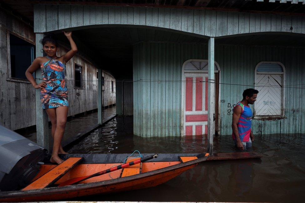 People are seen on a street flooded by the rising Solimoes river