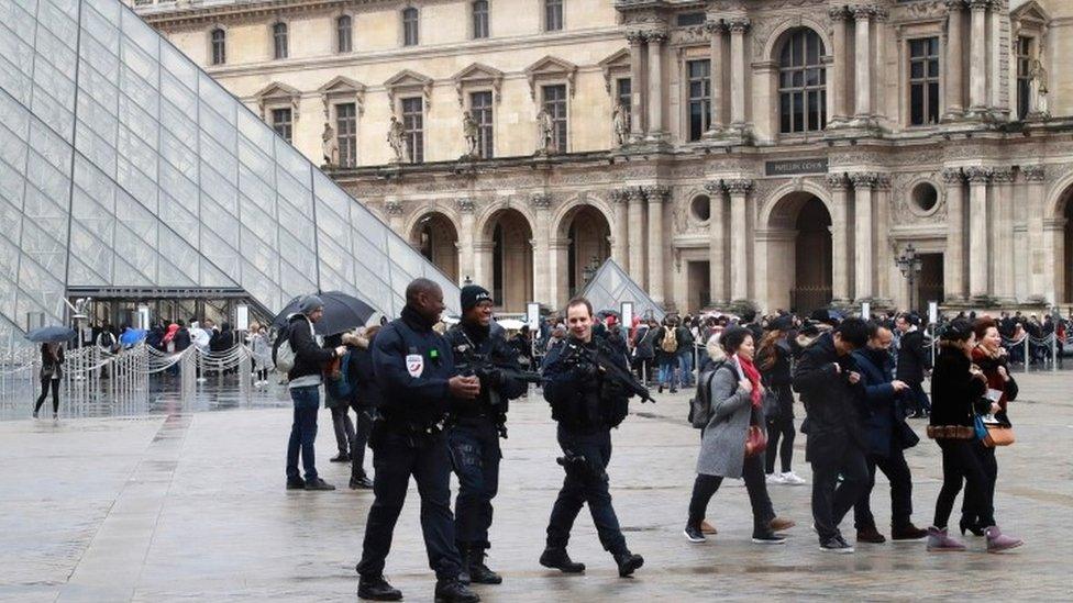 Police officers patrol in front of the Louvre Pyramid in Paris on 4 February, a day after a machete-wielding attacker lunged at four French soldiers.