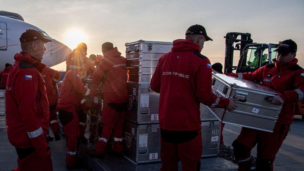 A group of firefighters load materials onto a plane