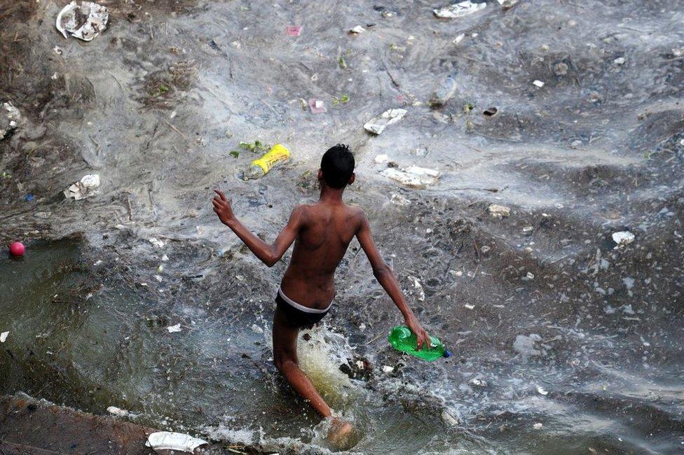 An Indian youth walks into polluted flood waters after the river Ganges rose following heavy monsoon rains in Allahabad on July 10, 2016.