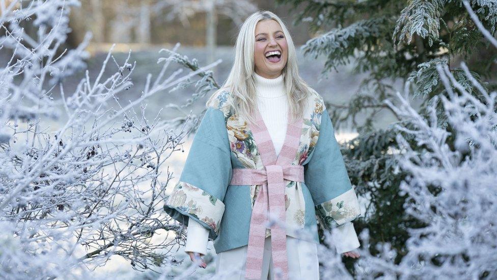 woman wears blue and pink kimono, standing among frosty trees