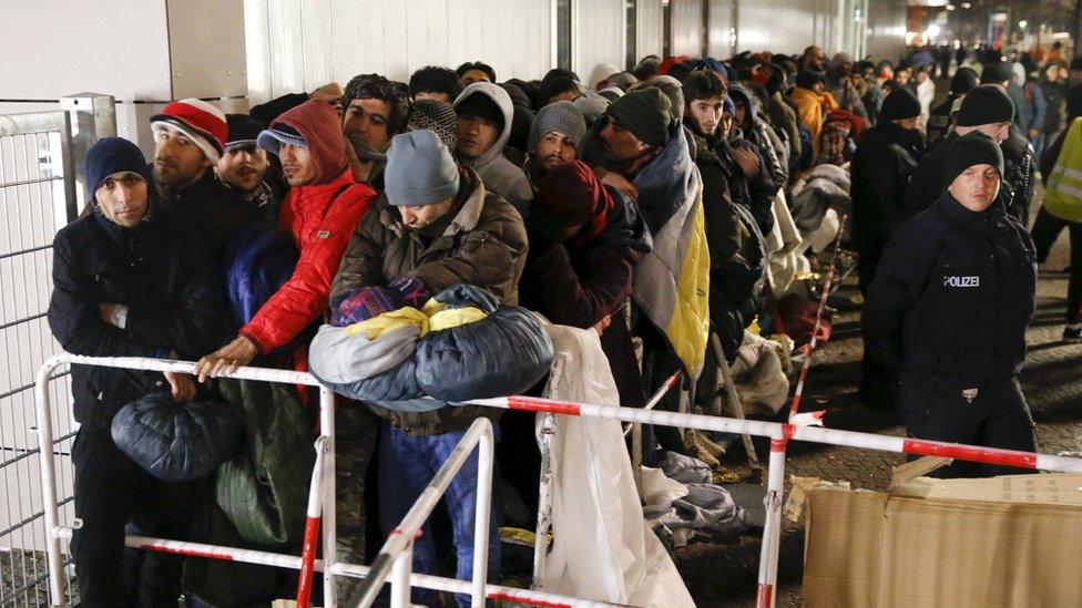 Migrants queue on a street to enter the compound outside the Berlin Office of Health and Social Affairs (LAGESO) for their registration process in Berlin, Germany