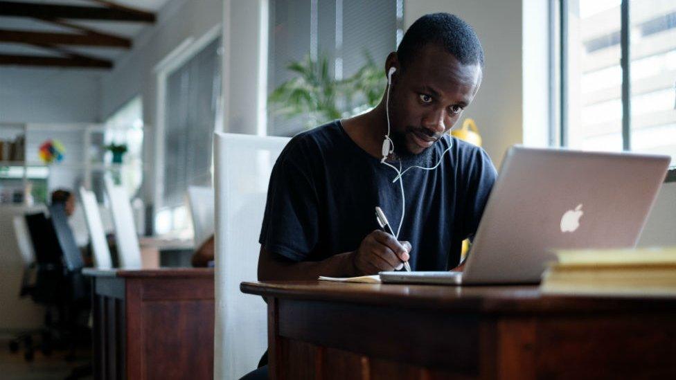 Young black South African sits at a computer